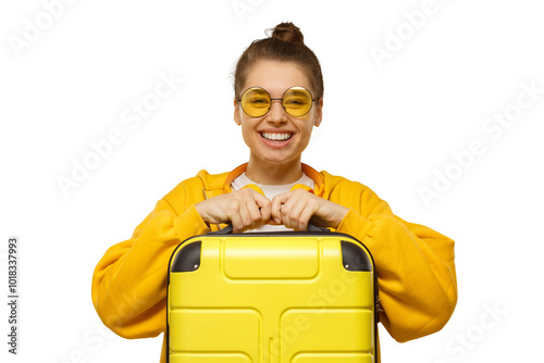 Young smiling woman in yellow hoodie and colored glasses holding travel suitcase, willing to go on trip photo