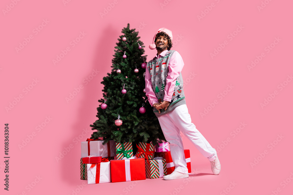 Full length photo of handsome good mood guy wear print vest santa hat celebrating noel xmas emtpy space isolated pink color background Full length photo of handsome good mood guy wear print vest santa hat celebrating noel xmas emtpy space isolated pink color background