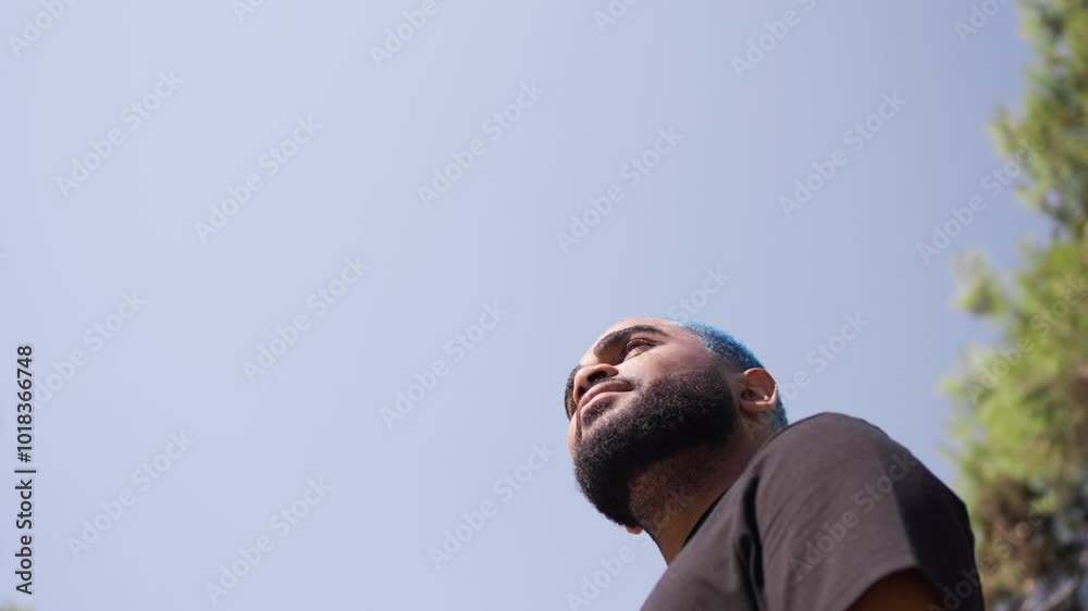 Extreme low angle portrait of black man head against blue sky looking around chilling in a park.MOV Extreme low angle portrait of black man head against blue sky looking around chilling in a park.MOV