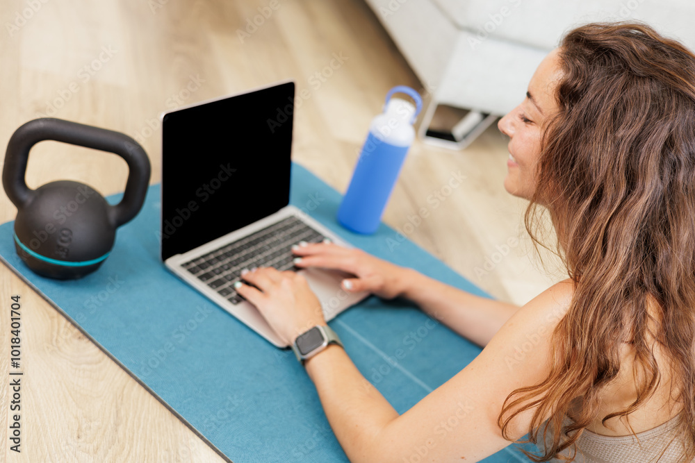 Young woman searching exercise routines on laptop at home. Online fitness trainer. Young woman searching exercise routines on laptop at home. Online fitness trainer.