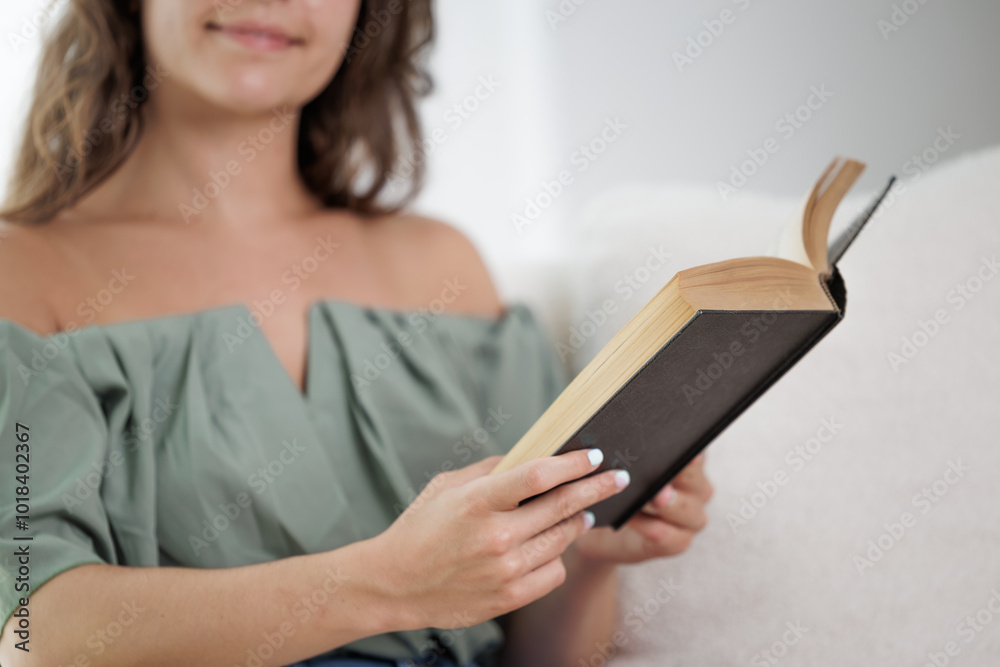Young woman reading an interesting book. The young man entertains himself by reading a book. He smiles because he likes the story of the book and imagines the protagonists. Dream, imagine. Young woman reading an interesting book. The young man entertains himself by reading a book. He smiles because he likes the story of the book and imagines the protagonists. Dream, imagine.