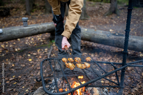 man cooking chicken on a campfire in the forest 