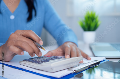 Businesswoman hand working with finances about cost and calculator and laptop with tablet on desk at office in morning light, Business accounting concept, Calculating or checking balance.