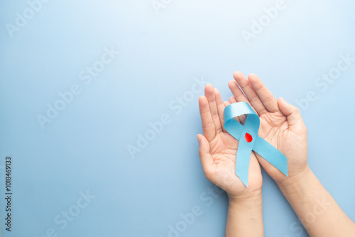 World diabetes day awareness concept. Hands holding blue ribbon with blood drop symbol for diabetes. Support for the fight against diabetes. photo