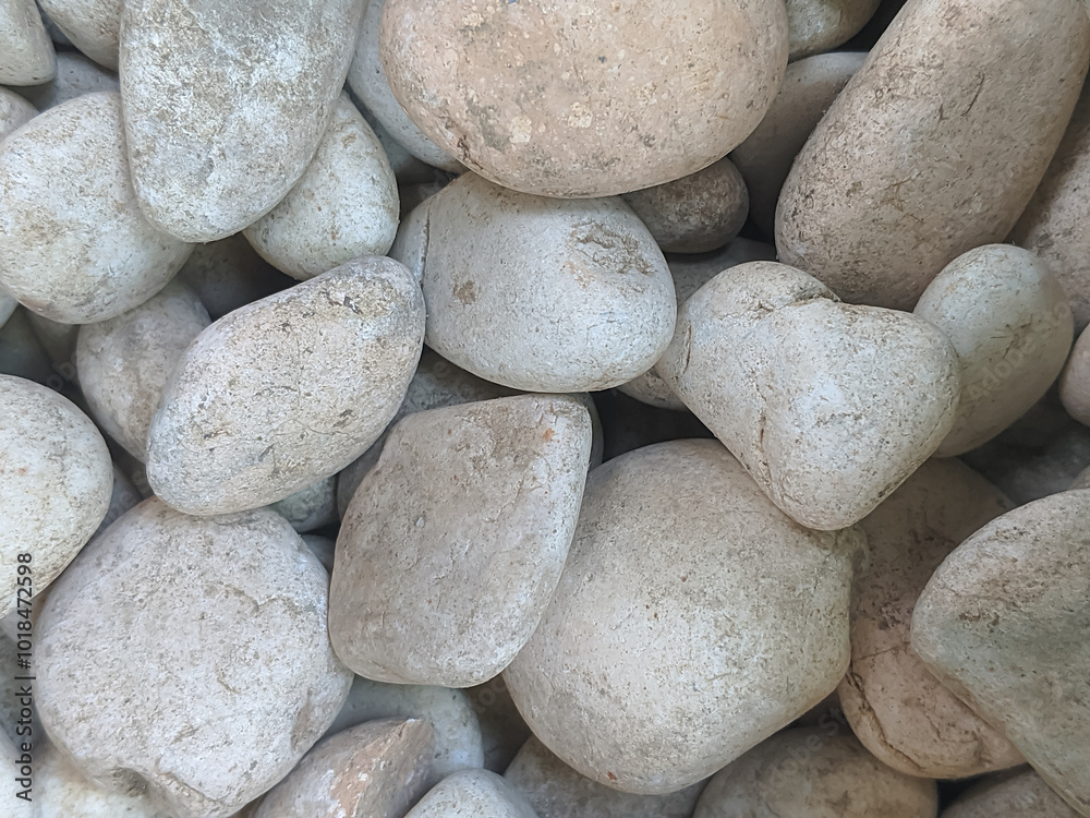 A close-up of smooth, rounded river rocks in various sizes, with a natural gray and white color palette. A close-up of smooth, rounded river rocks in various sizes, with a natural gray and white color palette.