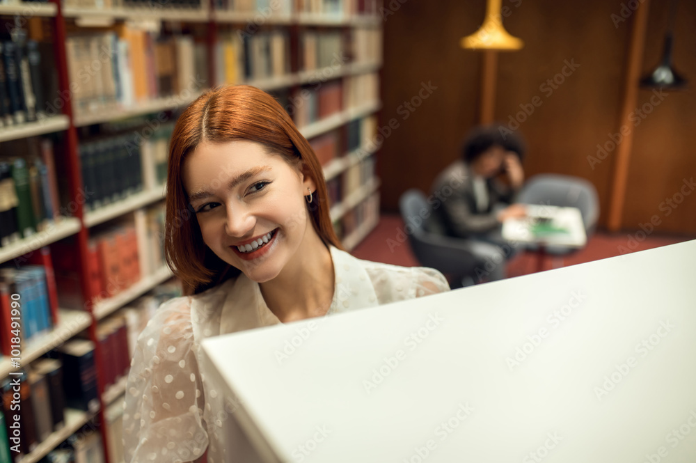 Ginger cute girl working in the library with her friend Ginger cute girl working in the library with her friend