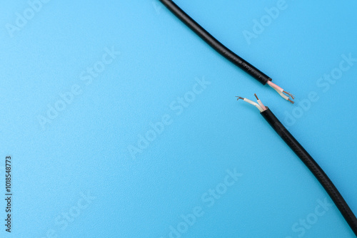 Two ends of a torn cable with a copper core, on a blue background. Broken cable requiring repair. Disconnection concept 