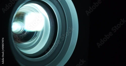 Cinema hall. Close-up of a working projector lens. Movie is shown through projector. Lenses of working projector change color. Light of different colors passes through lenses