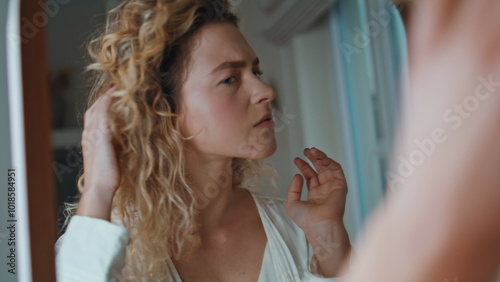 Woman looking bathroom mirror at home closeup. Concerned girl touching face skin