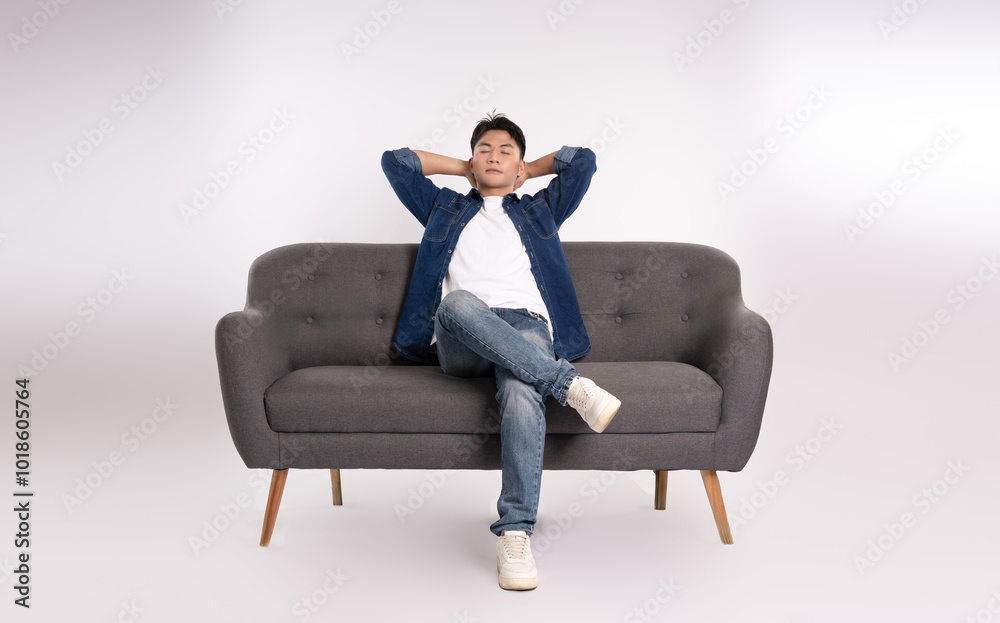 Full body image of young Asian man posing on sofa on white background Full body image of young Asian man posing on sofa on white background