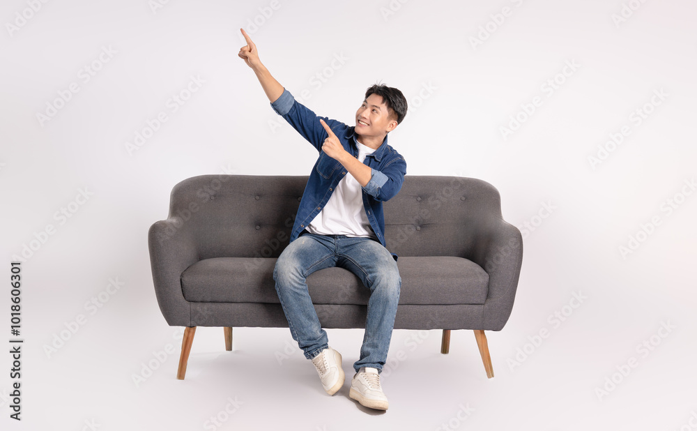 Full body image of young Asian man posing on sofa on white background Full body image of young Asian man posing on sofa on white background