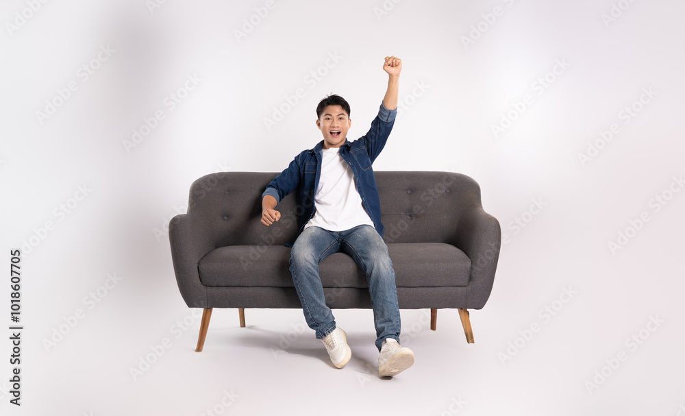 Full body image of young Asian man posing on sofa on white background Full body image of young Asian man posing on sofa on white background