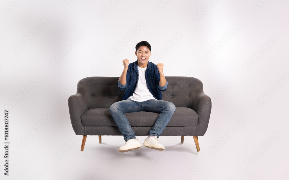Full body image of young Asian man posing on sofa on white background Full body image of young Asian man posing on sofa on white background