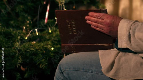 Woman reads Bible by decorated Christmas tree  photo