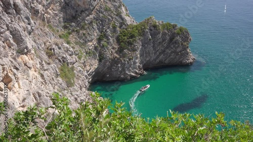 The boat, creating a small wake, is the focal point amidst the tranquil setting.