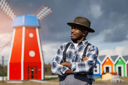 Portrait handsome African man farmer on background of traditional mill for wheat flour, eco farm