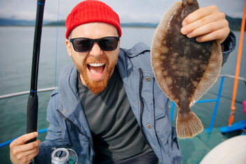 Happy Scandinavian fisherman caught flounder fish with fishing rod, trip Kamchatka Russia. Adventure action photo travel