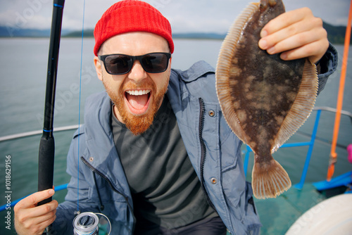 Papier peint Happy Scandinavian fisherman caught flounder fish with fishing rod, trip Kamchatka Russia