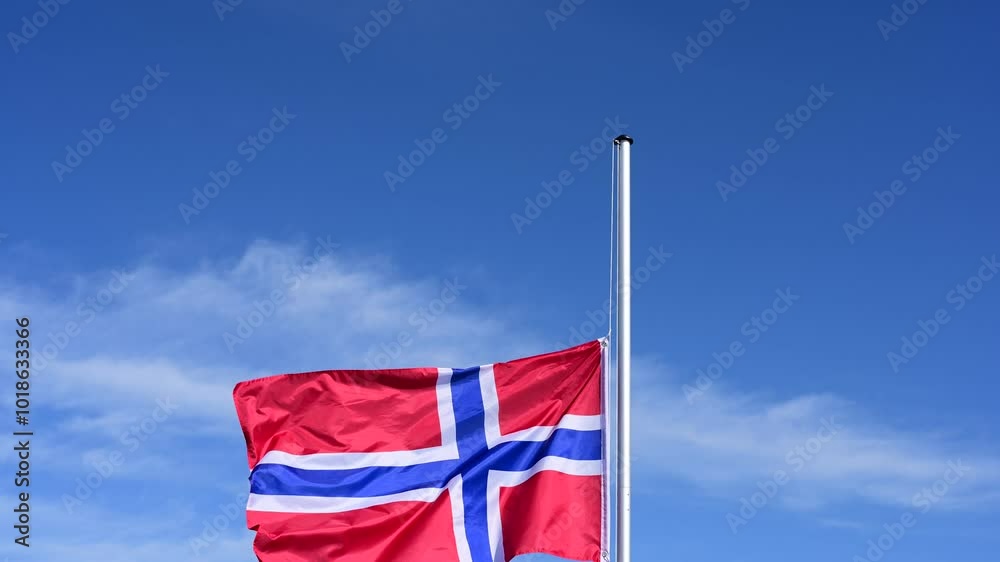 The flag of Norway is hoisted, flutters in the wind against a blue sky and is lowered again The flag of Norway is hoisted, flutters in the wind against a blue sky and is lowered again