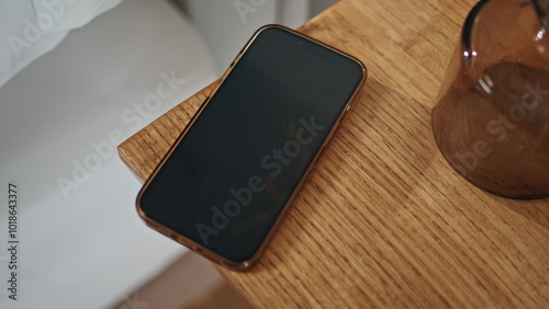 Fotografía Closeup smartphone wooden table in ambient bedroom setting