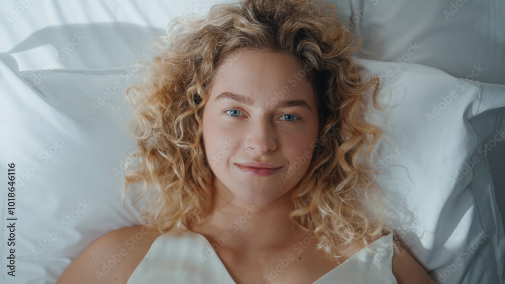 Attractive girl resting bed top view. Portrait smiling curly blonde waking up Attractive girl resting bed top view. Portrait smiling curly blonde waking up