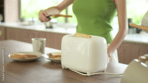 Asian woman preparing coffee and toast bread for breakfast at the kitchen table in the morning