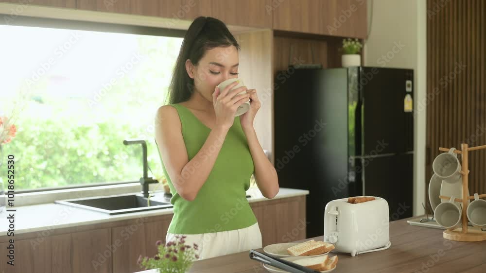 Asian woman preparing coffee and toast bread for breakfast at the kitchen table in the morning Asian woman preparing coffee and toast bread for breakfast at the kitchen table in the morning