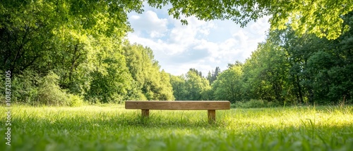 Fototapeta Naklejka Na Ścianę i Meble -   A wooden bench sits in the heart of a verdant field, surrounded by trees, and backed by a blue sky adorned with fluffy white clouds