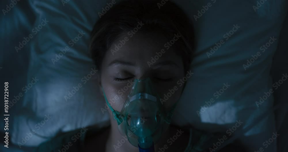 Female patient wearing oxygen mask looking directly at camera.