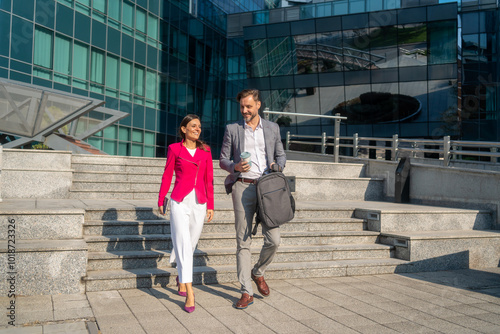 Business people, walking and travel in city with discussion on morning commute, partnership and happy. Employees, man and woman with conversation, collaboration and networking outdoor in urban city