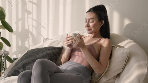 Young asian woman enjoying having coffee in living room at home