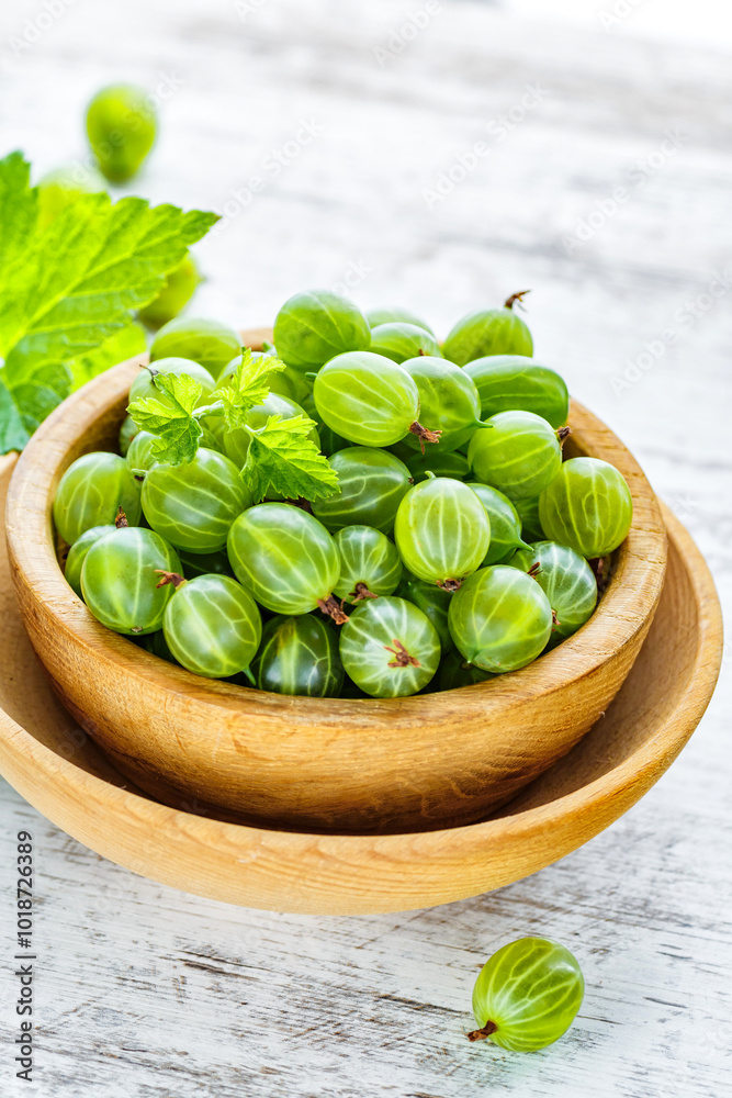 Green Organic Berries Gooseberries.Green gooseberries in a wooden bowl.Gooseberries on the wooden table. Harvest concept. Vegetarian food. Green Organic Berries Gooseberries.Green gooseberries in a wooden bowl.Gooseberries on the wooden table. Harvest concept. Vegetarian food.