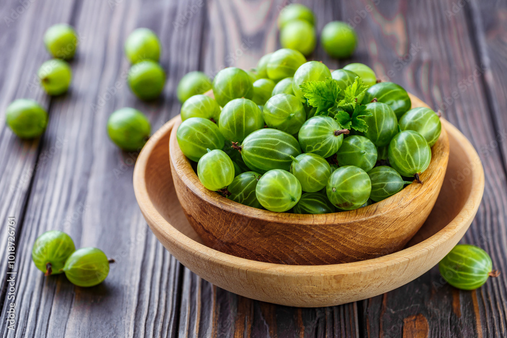 Green Organic Berries Gooseberries.Green gooseberries in a wooden bowl.Gooseberries on the wooden table. Harvest concept. Vegetarian food. Green Organic Berries Gooseberries.Green gooseberries in a wooden bowl.Gooseberries on the wooden table. Harvest concept. Vegetarian food.