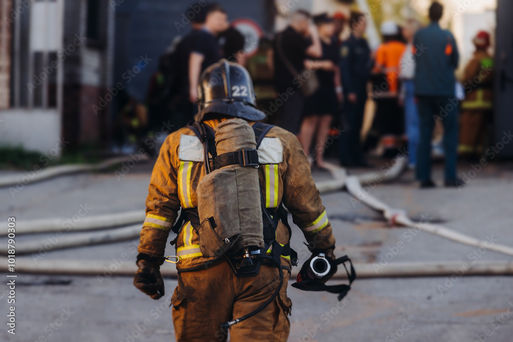 Group of fire men in uniform during fire fighting operation in the city streets, firefighters with the fire engine truck vehicle in the background, emergency and rescue, fire drill, exercise training Group of fire men in uniform during fire fighting operation in the city streets, firefighters with the fire engine truck vehicle in the background, emergency and rescue, fire drill, exercise training