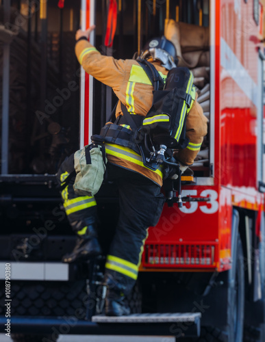 Group of fire men in uniform during fire fighting operation in the city streets, firefighters with the fire engine truck vehicle in the background, emergency and rescue, fire drill, exercise training