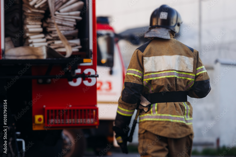 Group of fire men in uniform during fire fighting operation in the city streets, firefighters with the fire engine truck vehicle in the background, emergency and rescue, fire drill, exercise training Group of fire men in uniform during fire fighting operation in the city streets, firefighters with the fire engine truck vehicle in the background, emergency and rescue, fire drill, exercise training