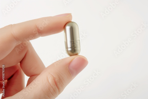 close-up of a woman's fingers, holding a big vitamin capsule on a white background