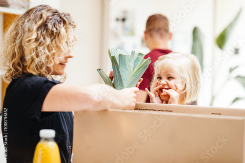 Parent And Child Enjoying Fresh Vegetables From A Cardboard Box photo