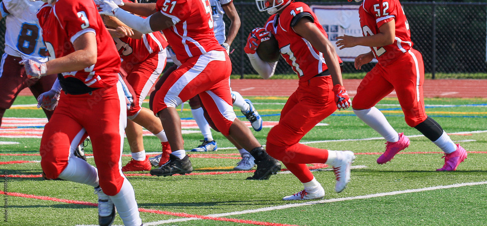 Football running back running toward the line of scrimage behind his blockers Football running back running toward the line of scrimage behind his blockers