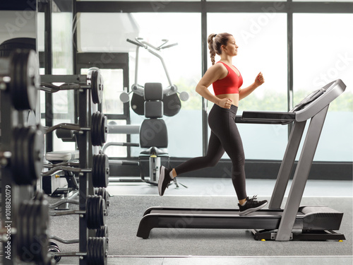 Strong young woman running on a treadmill at a gym