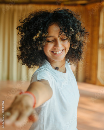 Smiling Woman with Curly Hair Reaching Forward in Indoor setting photo