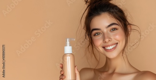 A smiling woman with glowing skin holds a skincare product bottle on minimal background with copy space, highlighting beauty and self-care.