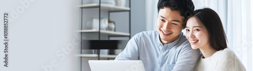 Smiling Asian couple enjoying their time together while working on a laptop.