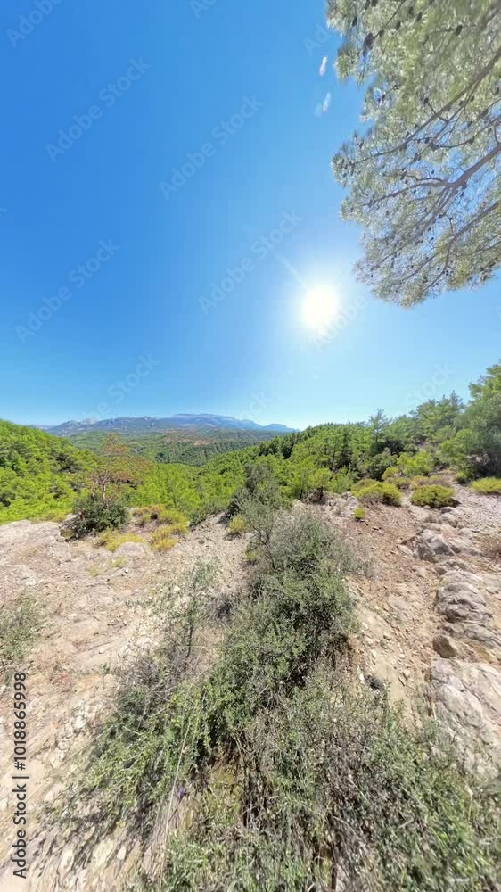 Walking along the cliff. The wide-angle perspective highlights the rugged terrain, greenery, and distant mountains beneath a bright sky. Walking along the cliff. The wide-angle perspective highlights the rugged terrain, greenery, and distant mountains beneath a bright sky.