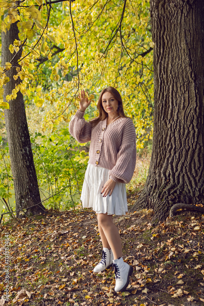 portrait of a woman in a dress standing in a park in autumn