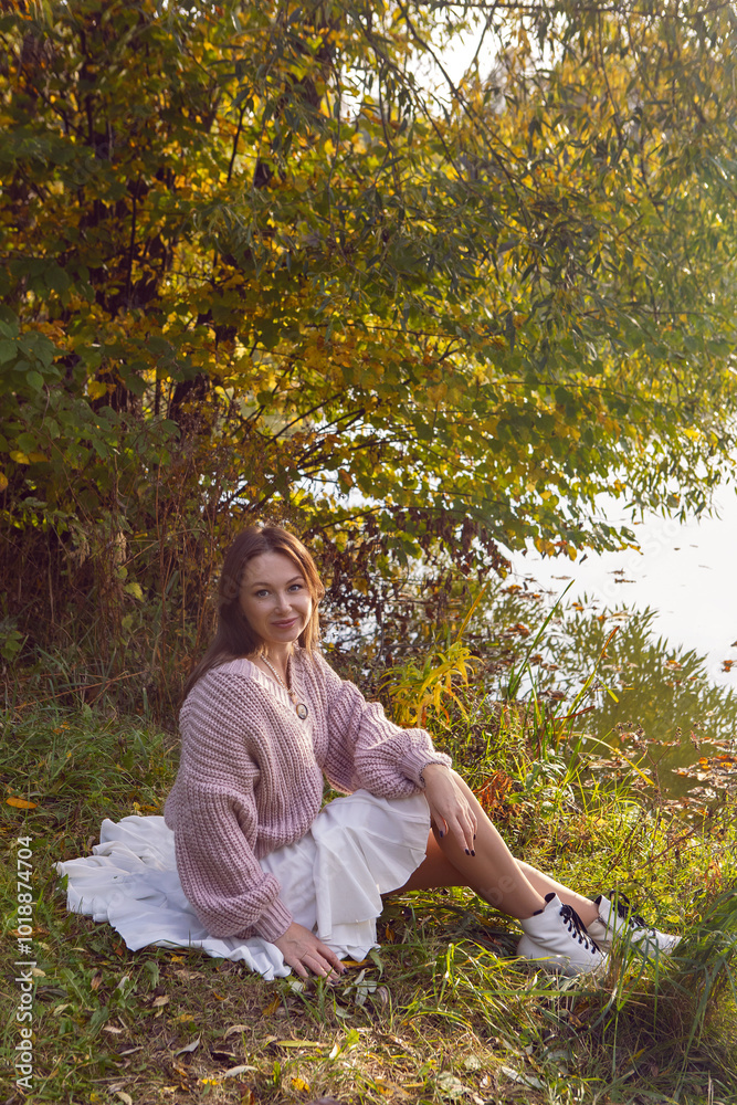 portrait of a woman in a dress sit in a park in autumn.