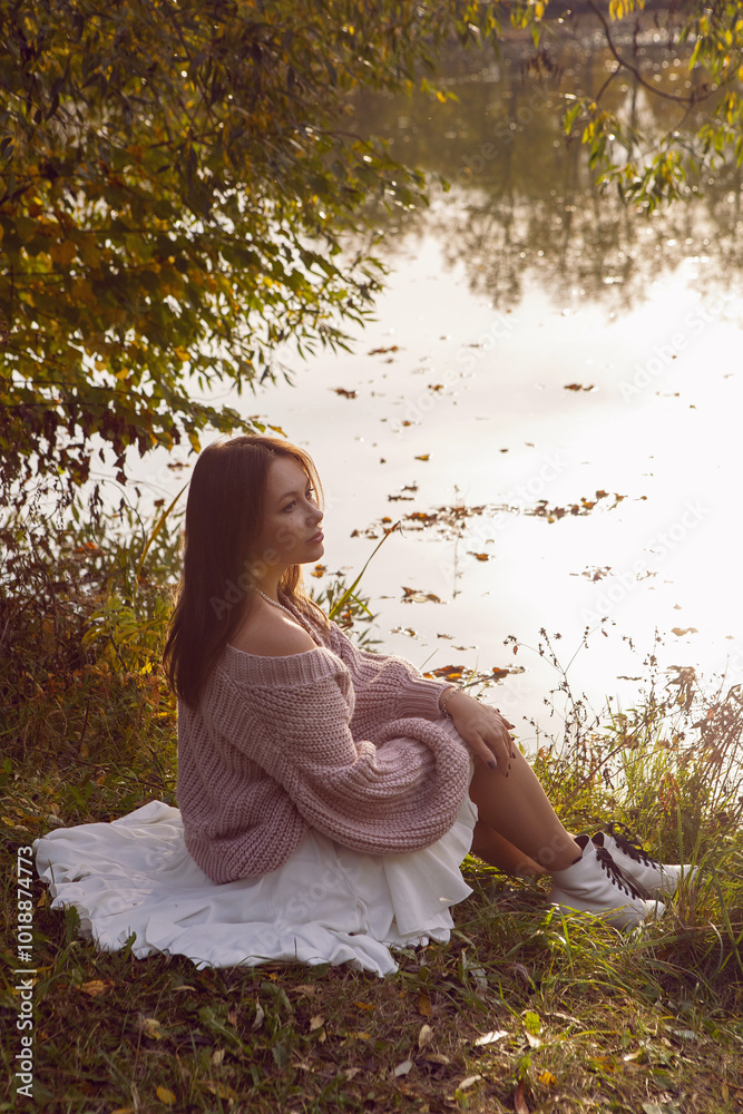 portrait of a woman in a dress sit in a park in autumn.