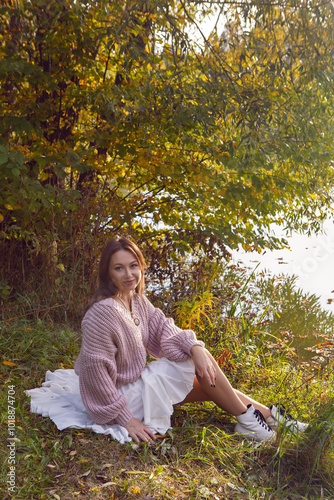 portrait of a woman in a dress sit in a park in autumn.