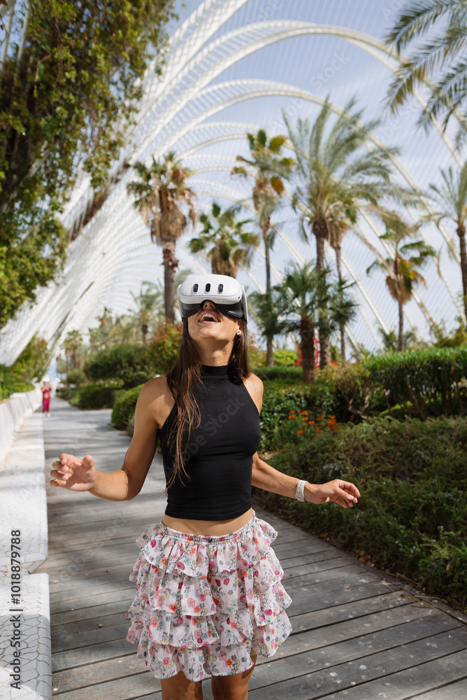 Fototapeta premium A young woman skating joyfully in a stylish summer outfit among palm trees on a sunny day
