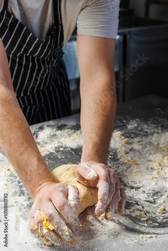 A chef in an apron kneads dough by hand, capturing the essence of the baking process. The focus is on the skillful technique of mixing ingredients, highlighting the traditional art of bread-making.